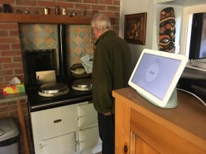 A man cooking with a smart home device behind him on the kitchen counter