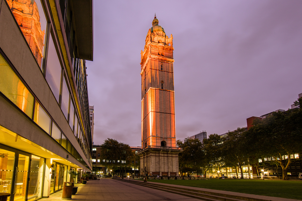 A photograph of Imperial's Queen's Tower light up in orange