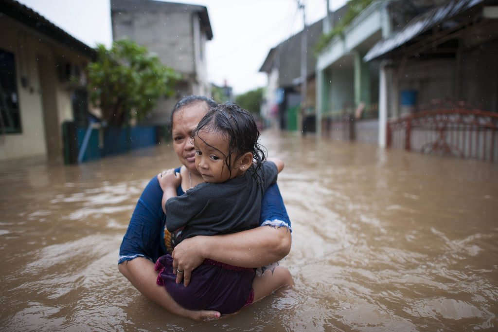 Woman carrying child in flood water due to climate change