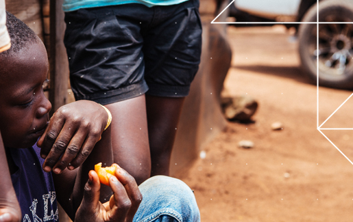 A young boy with undernutrition eating an orange